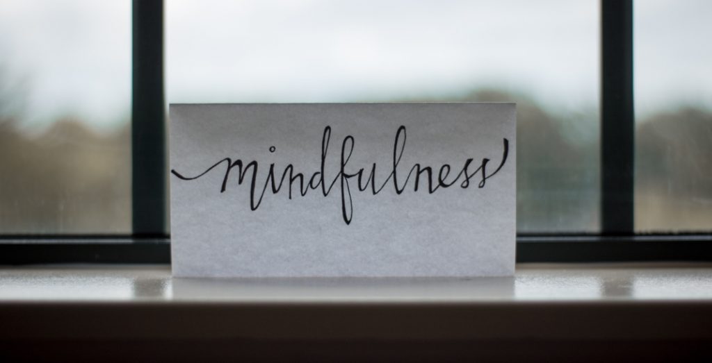 the word "mindfulness" written on a piece of paper propped against a window